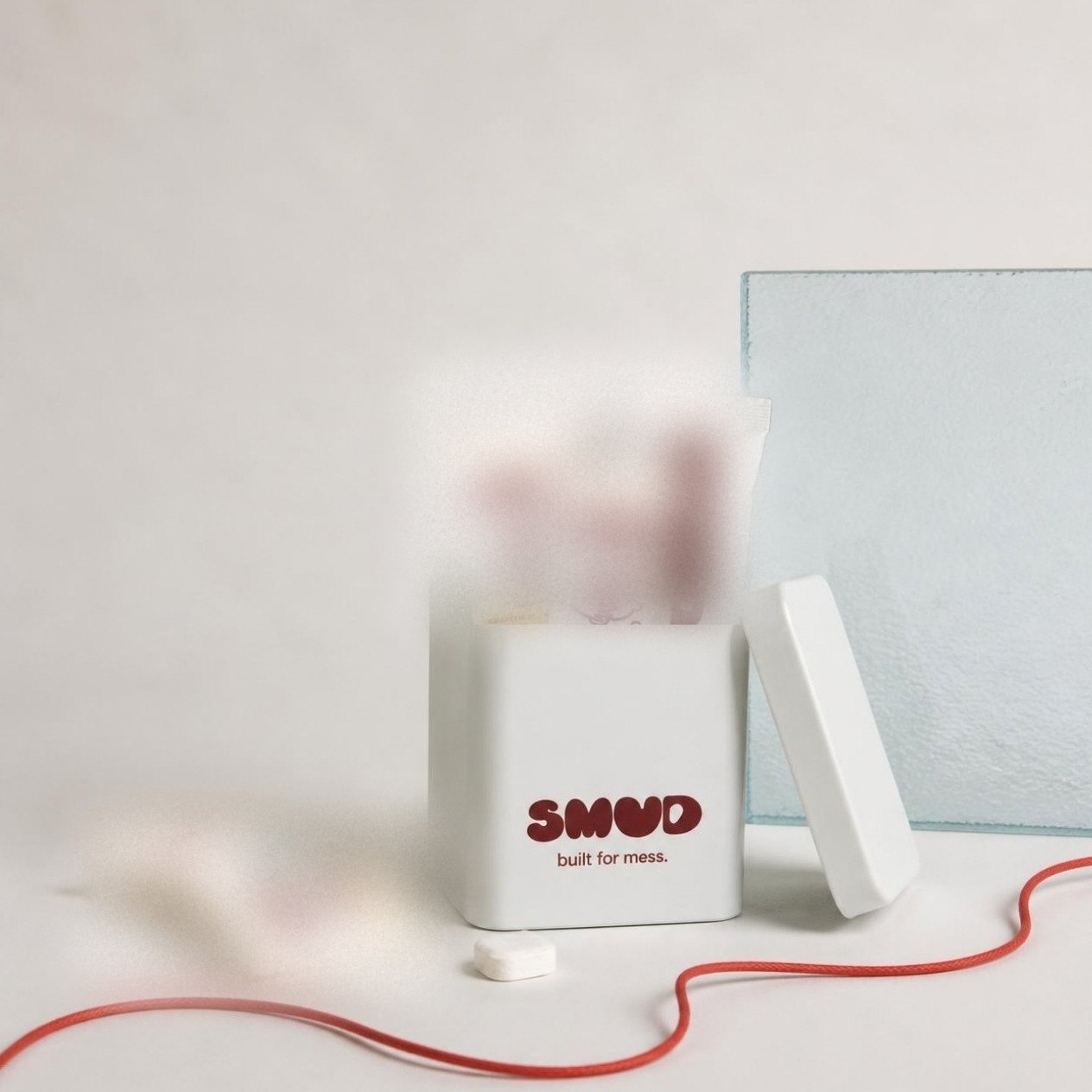 An open SMUD tin packed with refill sachets and dish sticks, a red cord across the table